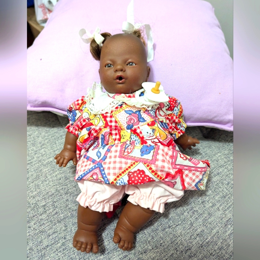 African doll with clothes and a soother. Unbranded. Cloth and plastic.